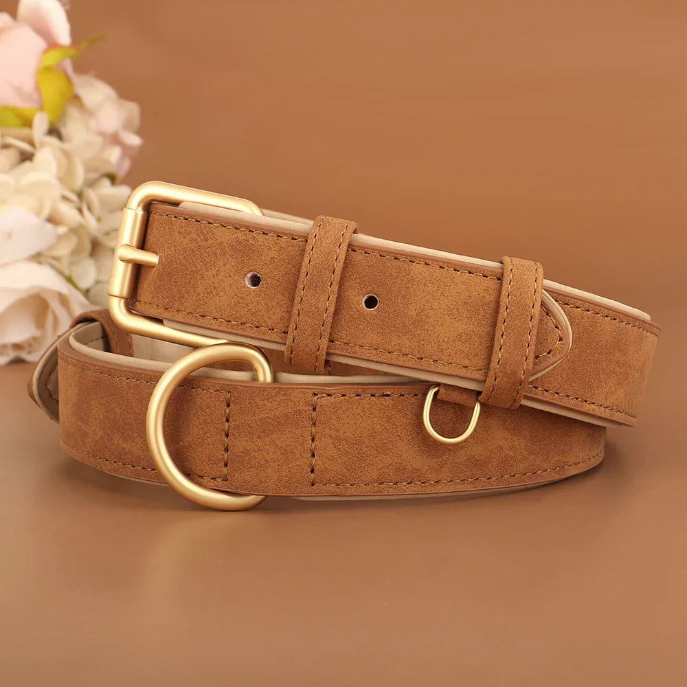 Ceinture en cuir marron avec boucle dorée, posée sur fond beige, accompagnée de fleurs blanches. Accessoire de mode élégant et tendance.
