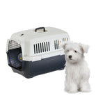 Chien blanc assis à côté d'une caisse de transport pour animaux, idéale pour voyages sécurisés. Accessoire essentiel pour propriétaires d'animaux.