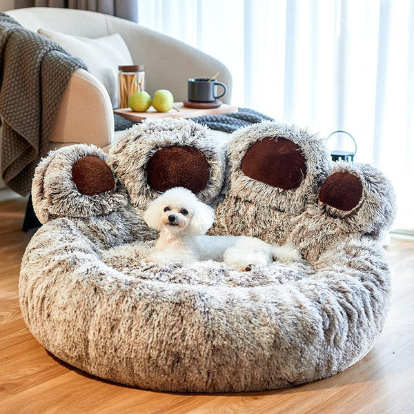 Petit chien blanc sur un lit pour chien en forme de patte, moelleux et gris, dans un salon moderne. Lit pour animaux, confort, design intérieur.