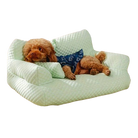 Chien allongé sur un canapé vert clair, portant un bandana bleu. Lit pour animaux de compagnie, confort, design moderne.